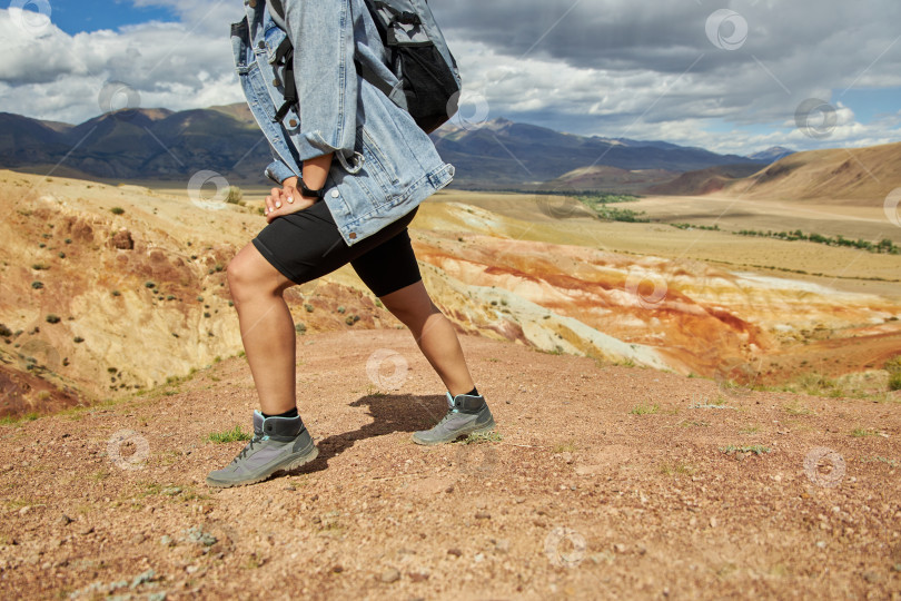 Скачать туристка в походных ботинках и джинсовой куртке взбирается на холм фотосток Ozero