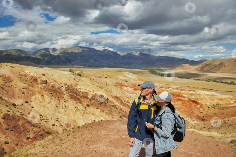 Скачать мужчина и женщина-туристы на фоне пустынного и холмистого ландшафта фотосток Ozero