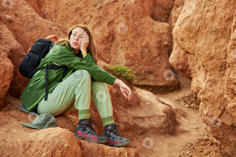 Скачать усталая туристка в мембранной куртке сидит в песчаном карьере фотосток Ozero