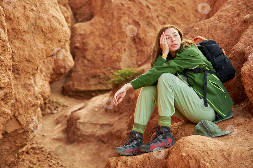Скачать усталая туристка в мембранной куртке сидит в песчаном карьере фотосток Ozero