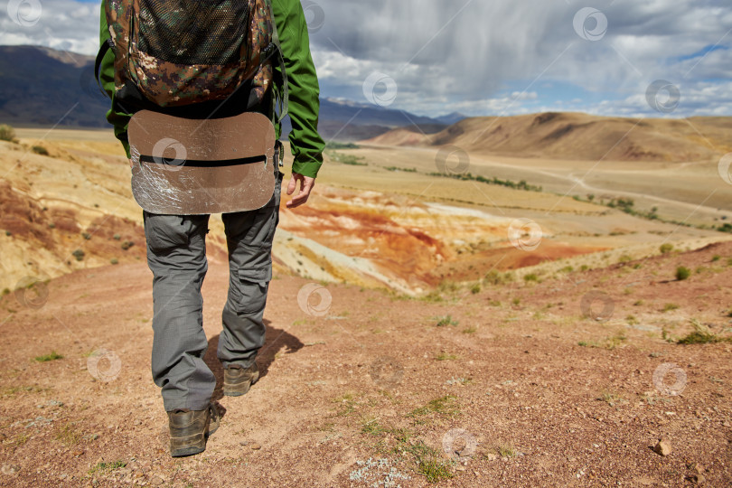 Скачать мужчина-турист спускается с холма на фоне пустынного холмистого пейзажа фотосток Ozero