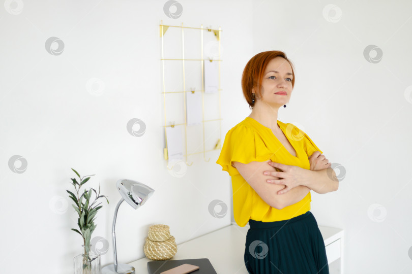 Скачать женщина в блузке стоит у стола на фоне белой стены фотосток Ozero