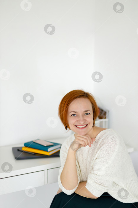 Скачать рыжеволосая женщина в белом свитере сидит и улыбается фотосток Ozero