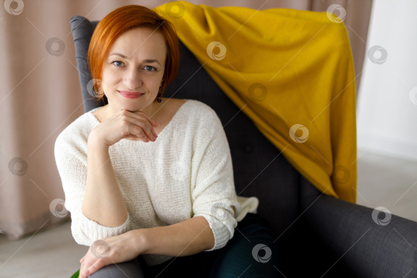 Скачать женщина сидит в кресле, смотрит в камеру и улыбается фотосток Ozero