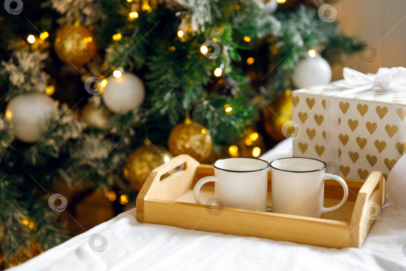 Скачать деревянный поднос и две белые кружки на кровати на белой простыне фотосток Ozero