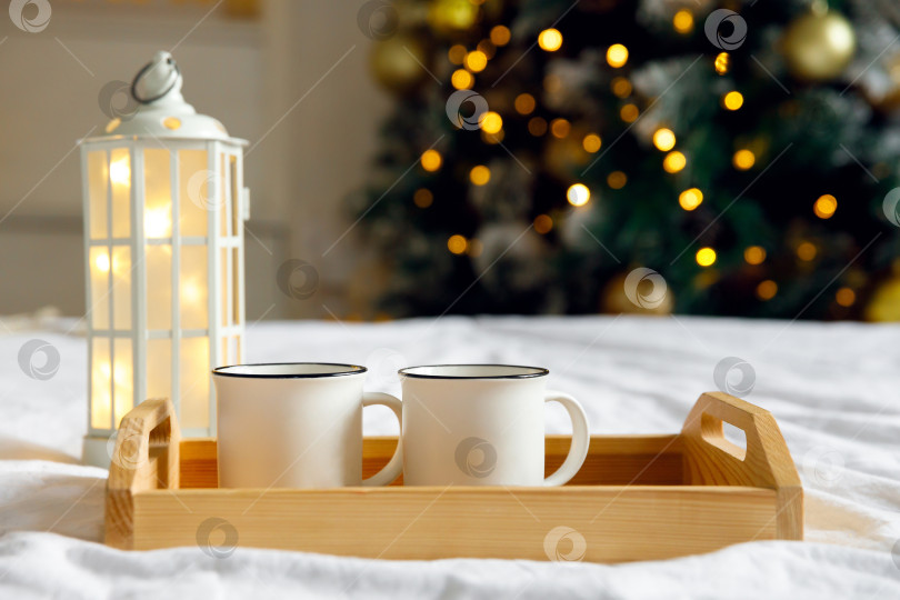 Скачать деревянный поднос и две белые кружки на кровати на белой простыне фотосток Ozero