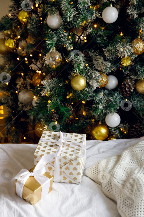 Скачать Рождественские подарки на кровати на белой простыне, рядом с украшенной рождественской елкой фотосток Ozero