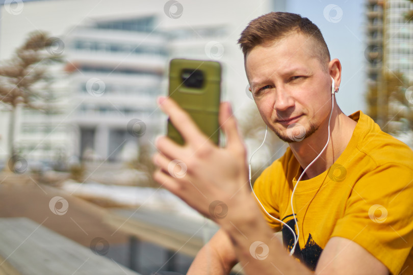 Скачать мужчина-студент со смартфоном в руках и наушниках фотосток Ozero