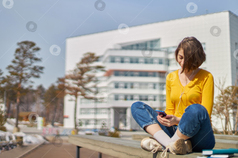 Скачать студентка со смартфоном в руках и наушниках фотосток Ozero