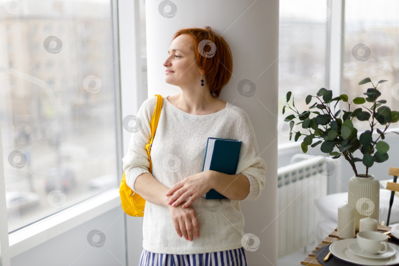 Скачать женщина в свитере и с сумкой на плече, держит блокнот фотосток Ozero