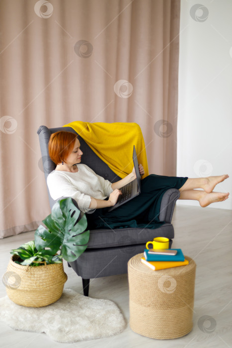 Скачать женщина сидит в кресле, работает за ноутбуком фотосток Ozero