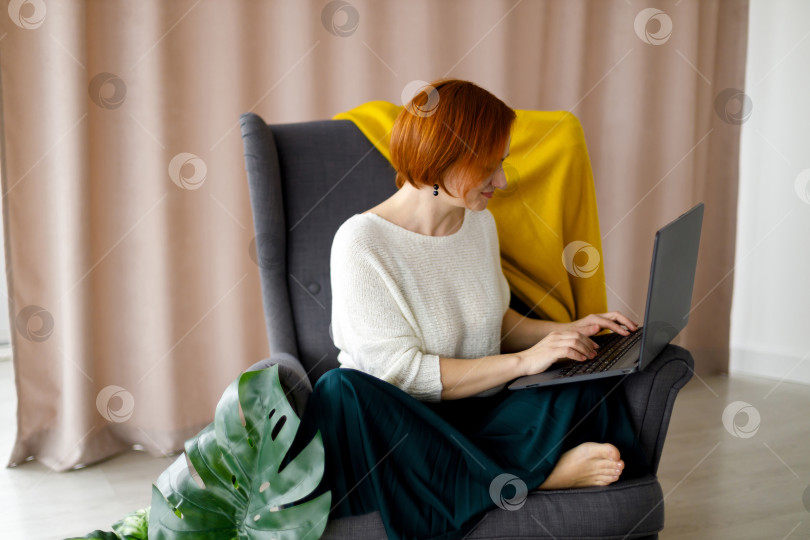 Скачать женщина сидит в кресле, работает за ноутбуком фотосток Ozero