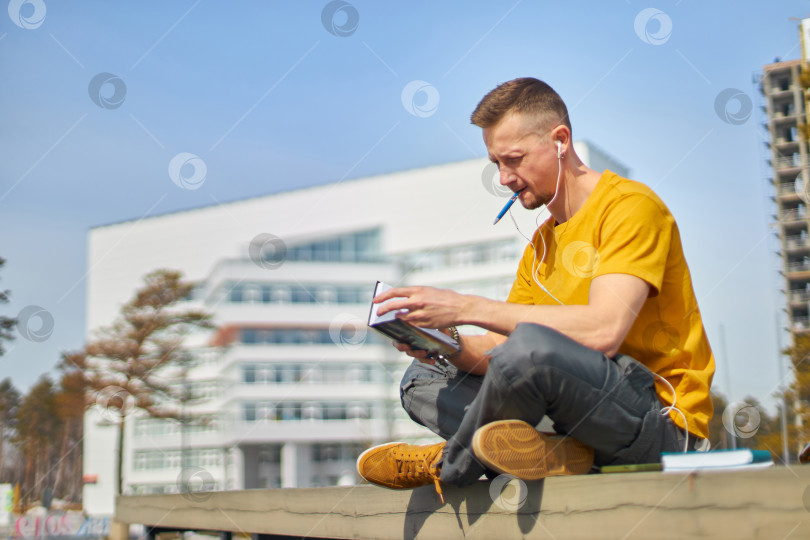 Скачать мужчина-студент со смартфоном в руках и наушниках фотосток Ozero