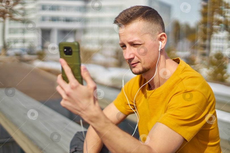 Скачать мужчина-студент со смартфоном в руках и наушниках фотосток Ozero