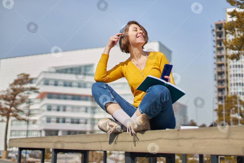 Скачать студентка со смартфоном в руках и наушниках фотосток Ozero