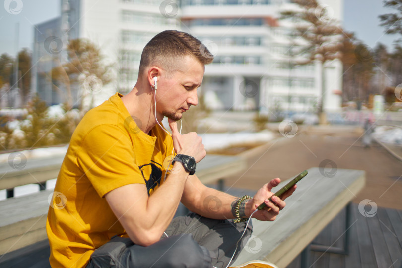 Скачать мужчина-студент со смартфоном в руках и наушниках фотосток Ozero