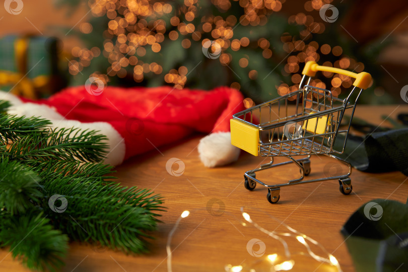 Скачать Шапка Санты, ветка рождественской елки и небольшая продуктовая тележка фотосток Ozero