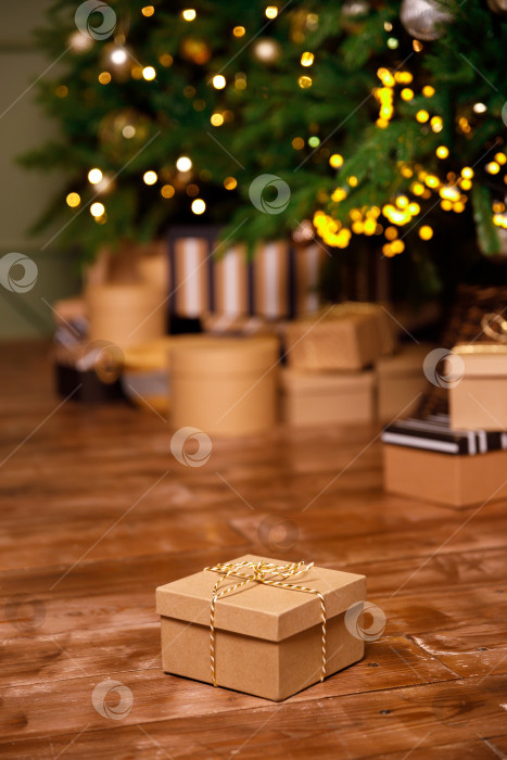 Скачать рождественский подарок в картонной коробке на деревянном полу рядом с елкой фотосток Ozero
