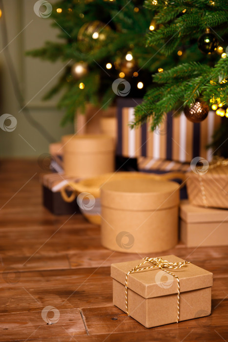 Скачать рождественский подарок в картонной коробке на деревянном полу возле новогодней елки фотосток Ozero