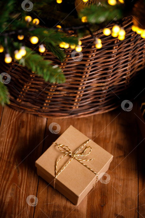 Скачать рождественский подарок в картонной коробке на деревянном полу возле новогодней елки фотосток Ozero