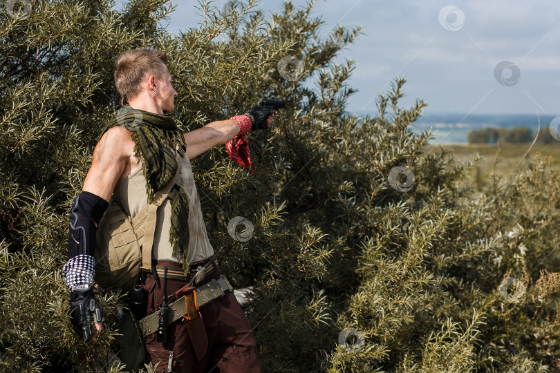 Скачать мужчина в грязной одежде прячется в кустах и стреляет из пистолета фотосток Ozero