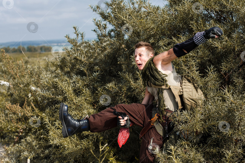 Скачать мужчина в грязной одежде прячется в кустах и стреляет из пистолета фотосток Ozero