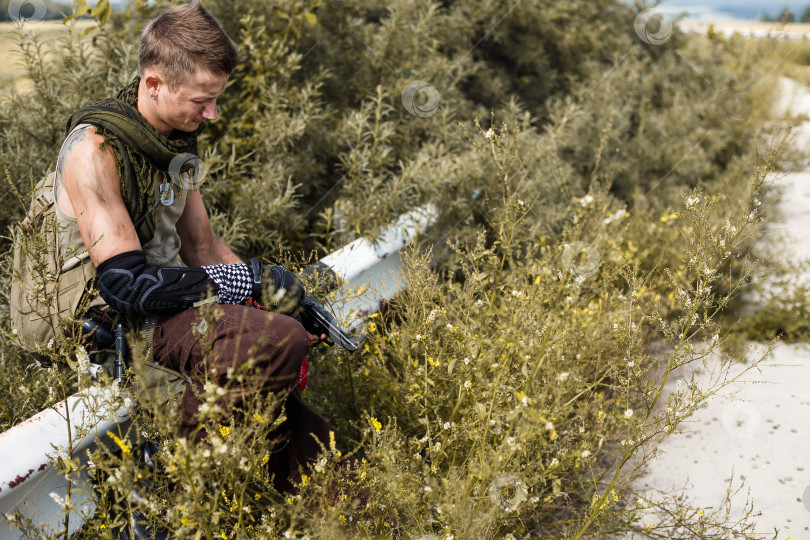 Скачать мужчина-вандал в грязной одежде и с пистолетом сидит на заборе фотосток Ozero