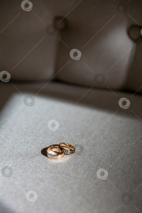 Скачать обручальные кольца лежат на диване, освещенные яркими контрастными лучами солнца фотосток Ozero