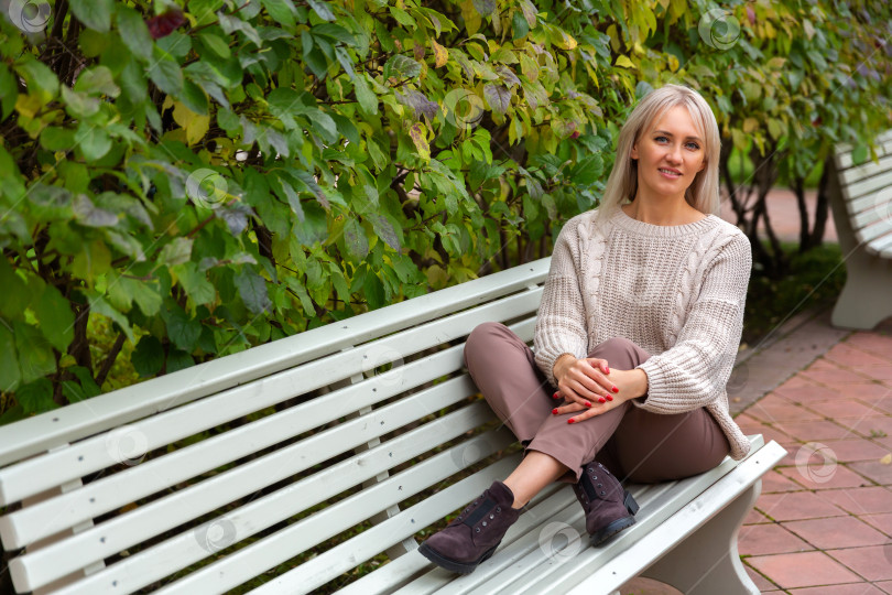 Скачать Молодая красивая женщина сидит на скамейке в парке фотосток Ozero