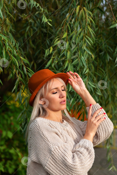 Скачать женщина в свитере стоит под ветвями и листьями фотосток Ozero