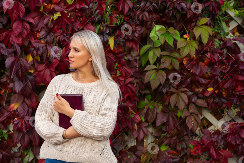 Скачать женщина стоит с книгой в руках возле виноградной лозы с листьями фотосток Ozero