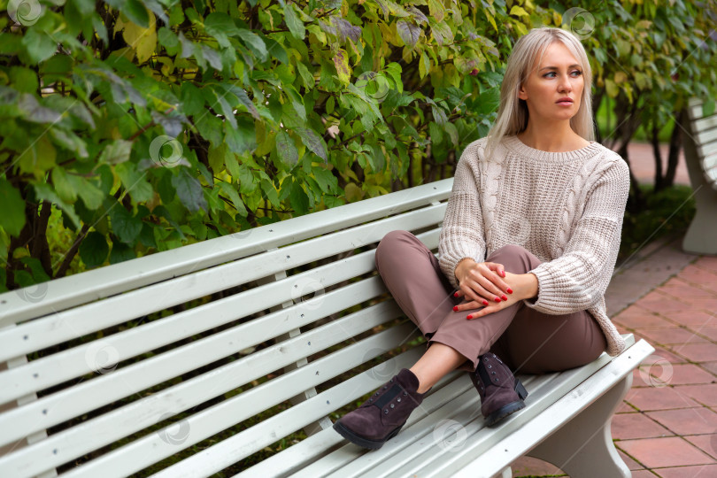 Скачать Молодая красивая женщина сидит на скамейке в парке фотосток Ozero