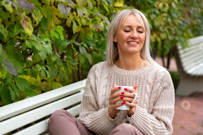 Скачать Молодая красивая женщина сидит на скамейке в парке фотосток Ozero