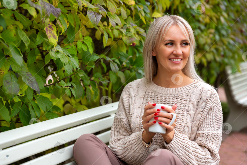 Скачать Молодая красивая женщина сидит на скамейке в парке фотосток Ozero