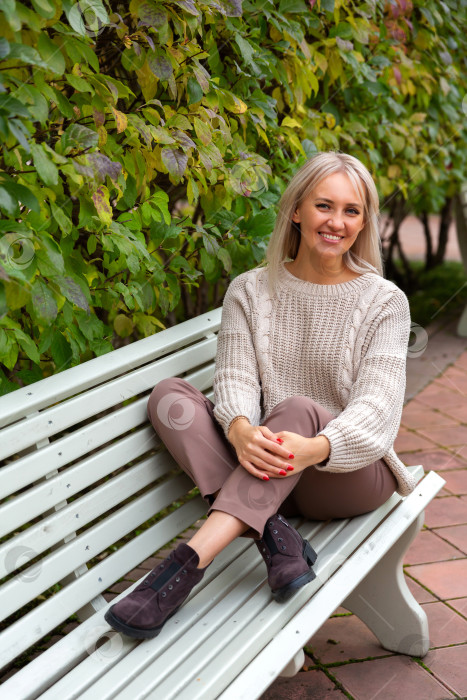 Скачать Молодая красивая женщина сидит на скамейке в парке фотосток Ozero