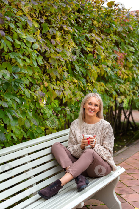 Скачать Молодая красивая женщина сидит на скамейке в парке фотосток Ozero