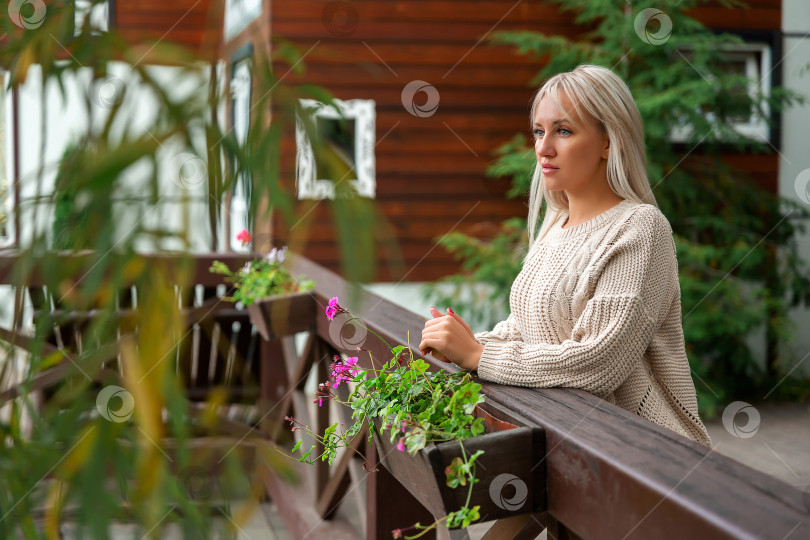 Скачать женщина положила руки на деревянный балкон, печально смотрит по сторонам фотосток Ozero