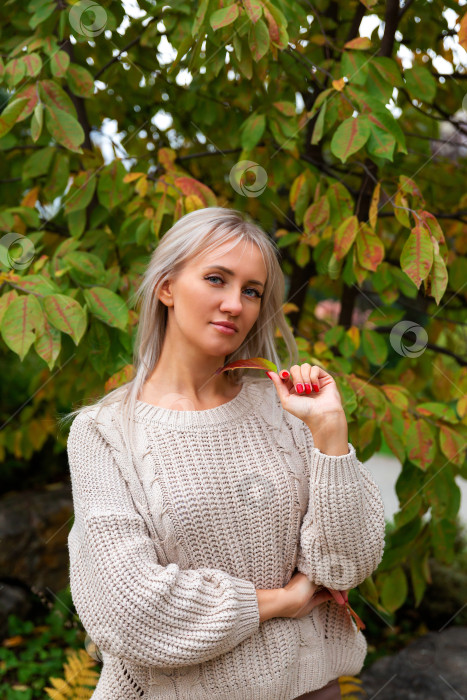 Скачать женщина в свитере держит в руке листок, глядя в сторону. фотосток Ozero