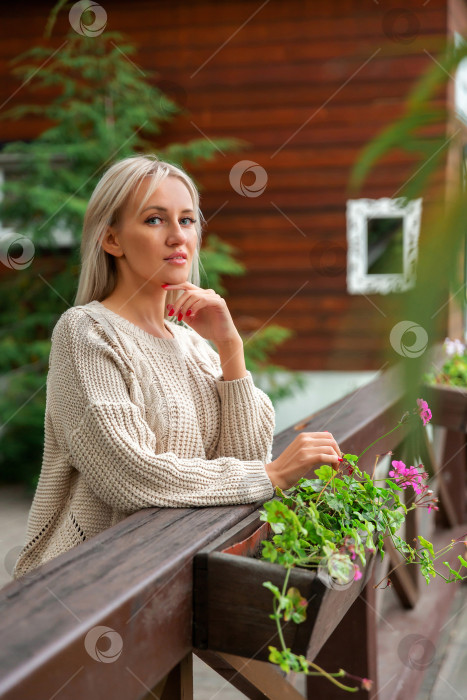 Скачать женщина положила руки на деревянный балкон и смотрит в камеру фотосток Ozero