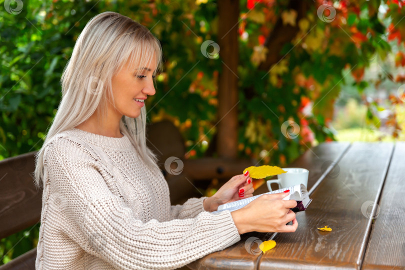 Скачать женщина в свитере сидит в беседке и читает книгу фотосток Ozero