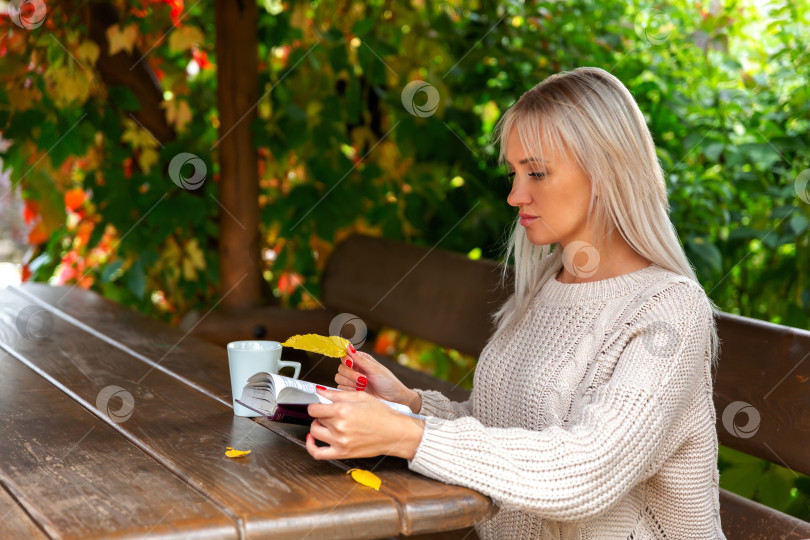 Скачать женщина в свитере сидит в беседке и читает книгу фотосток Ozero