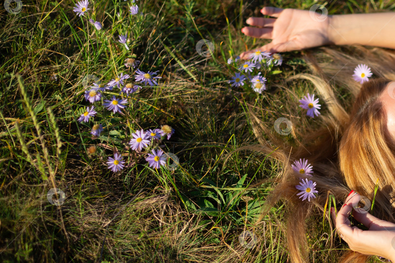 Скачать женщина лежит на траве в маргаритках, подняв руки над головой фотосток Ozero