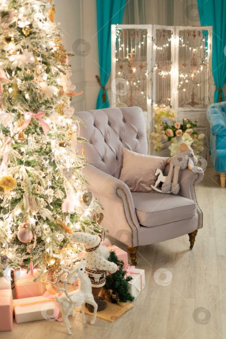 Скачать кресло стоит рядом с рождественской елкой, украшенной гирляндой и игрушками фотосток Ozero