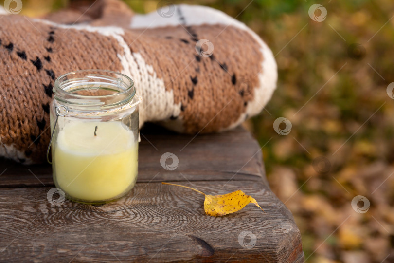 Скачать вязаная одежда и свеча в банке на деревянной скамейке в парке. Осенний теплый шерстяной свитер фотосток Ozero