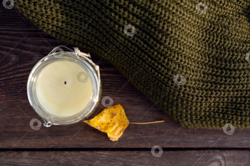 Скачать вязаная одежда и свеча в банке на деревянной скамье. Осенний теплый шерстяной свитер фотосток Ozero