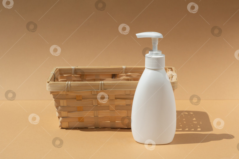 Скачать плетеная корзина и белый флакон-дозатор для спа-косметики на бежевом фоне фотосток Ozero