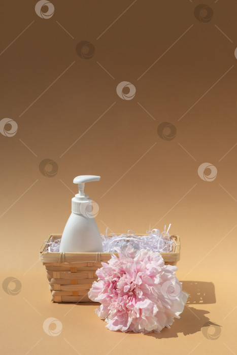 Скачать Белый флакон в плетеной корзинке. Крупный бутон розового пиона. Косметика и парфюмерия. Уход за телом и кожей. Концепция спа, массаж фотосток Ozero