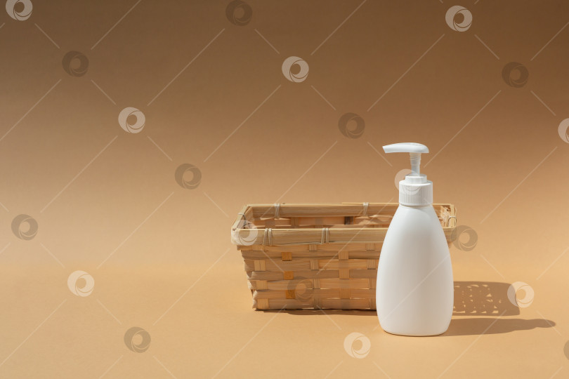 Скачать плетеная корзина и белый флакон-дозатор для спа-косметики на бежевом фоне фотосток Ozero