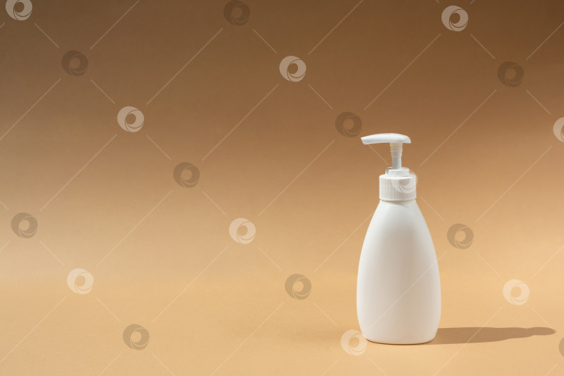 Скачать белый флакон-дозатор для спа-косметики на бежевом или коричневом фоне. Антибактериальное мыло. Место для вашего текста фотосток Ozero