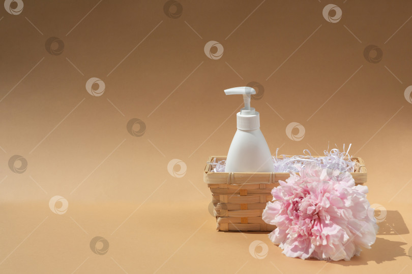Скачать Белый флакон в плетеной корзинке. Крупный бутон розового пиона. Косметика и парфюмерия. Уход за телом и кожей. Концепция спа, массаж фотосток Ozero